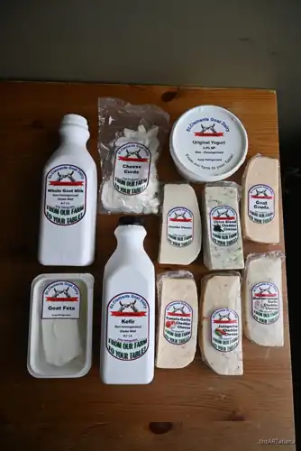 Local whole goat milk, goat kefir, yogurt, feta and goat cheeses from a family goat dairy, laid out on a wooden table at Natura Corner