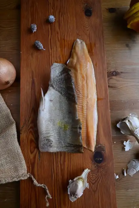 Wild-caught Lake Superior trout fillet and skin-on whitefish fillet on a wooden board at Natura Corner
